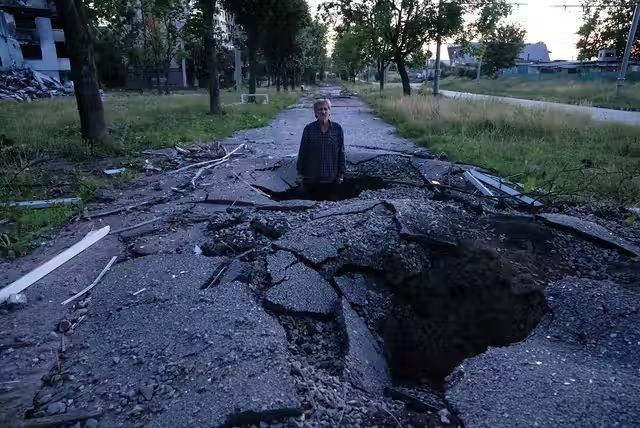 A man stands in a crater after a Russian attack in Kharkiv, Ukraine, on July 1, 2022. (AP Photo/Evgeniy Maloletka)